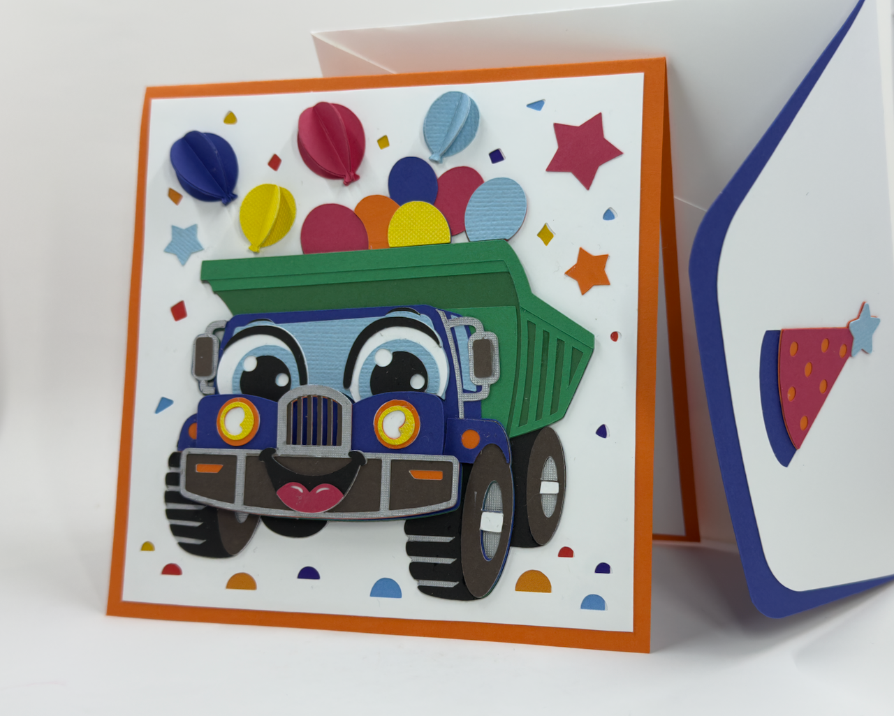 A colorful birthday card featuring a cartoon dump truck with balloons and birthday decorations.